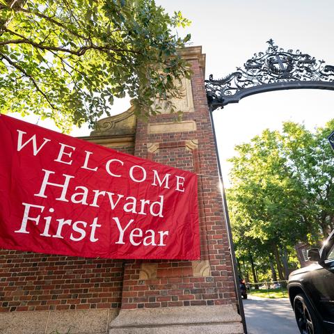 Car driving through campus gate with sign that reads "Welcome Harvard First-Year"