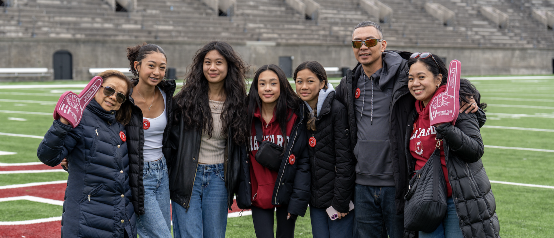 Student family taking a group picture at the Harvard Stadium during Family Weekend block party.