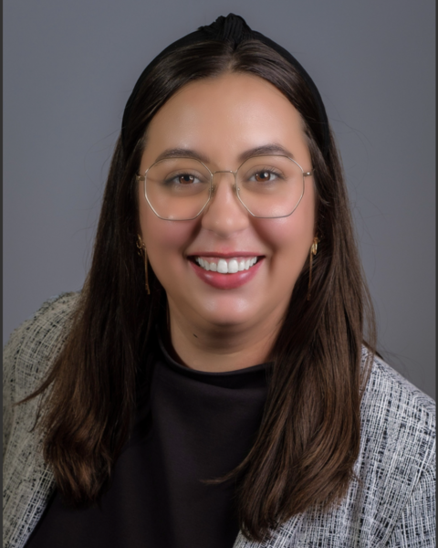 a smiling woman wearing glasses and a sweater